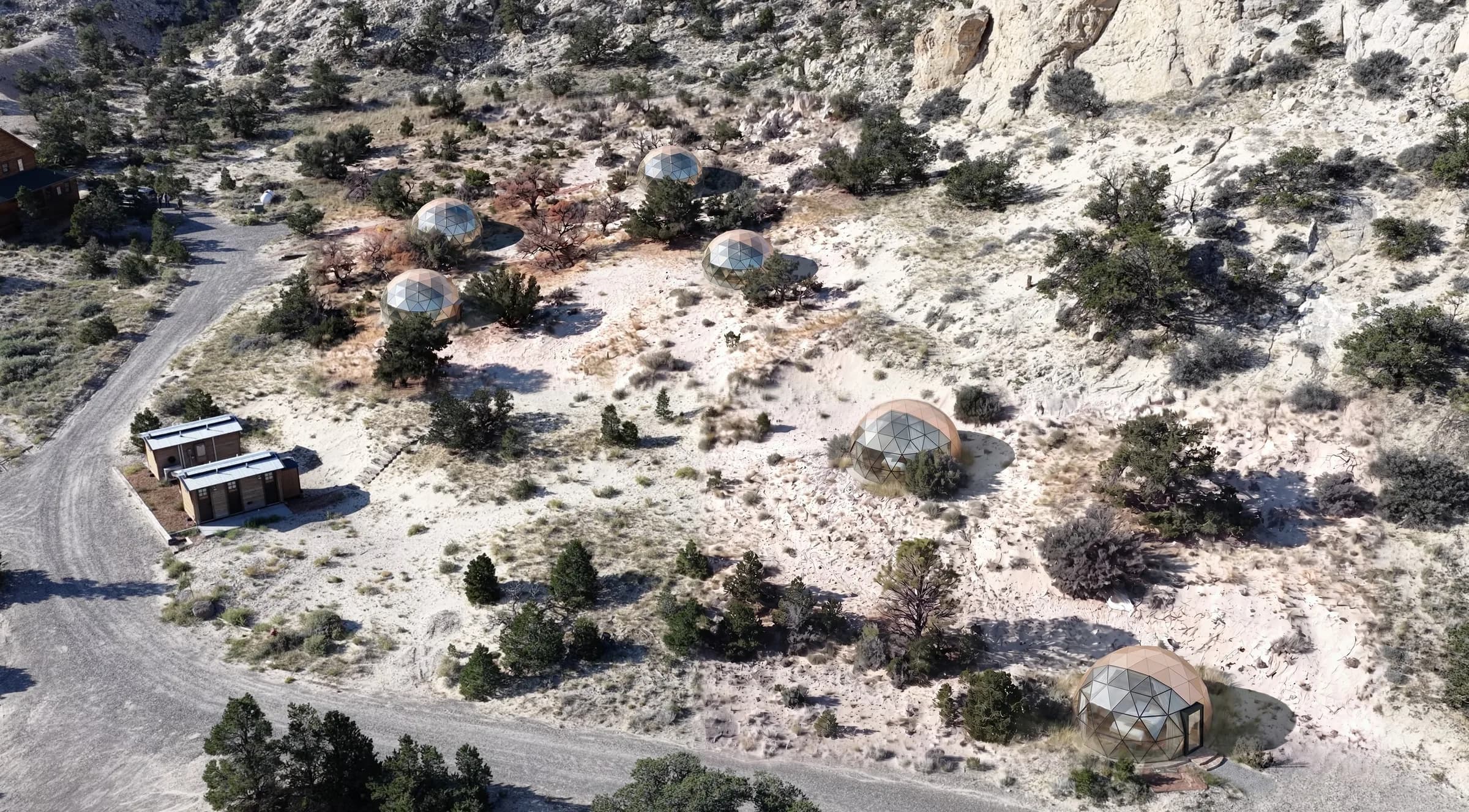 Visualisation of six planned glass geodesic domes on the existing glamping sites, seen from above among junipers near Torrey, Utah