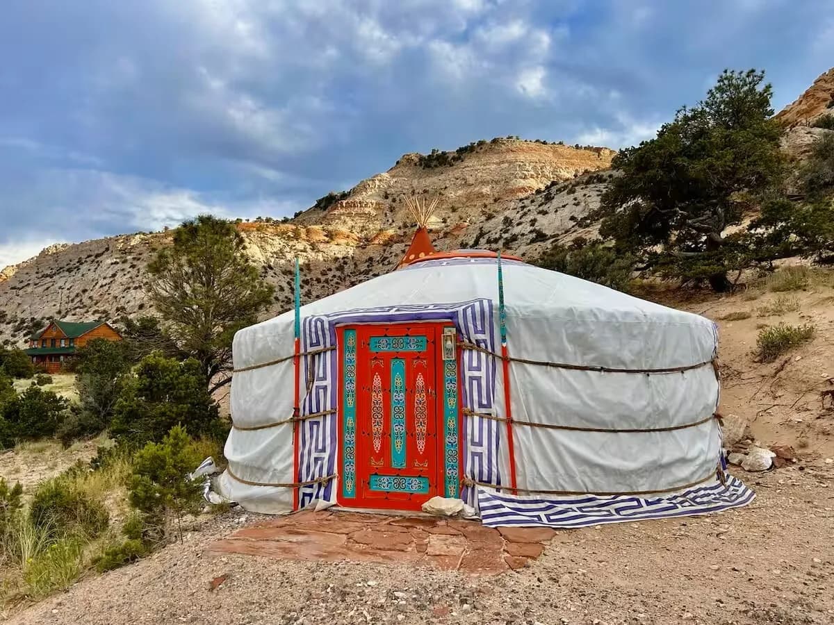 The Roadside Mongolian yurt with its painted orange door below the sandstone cliff