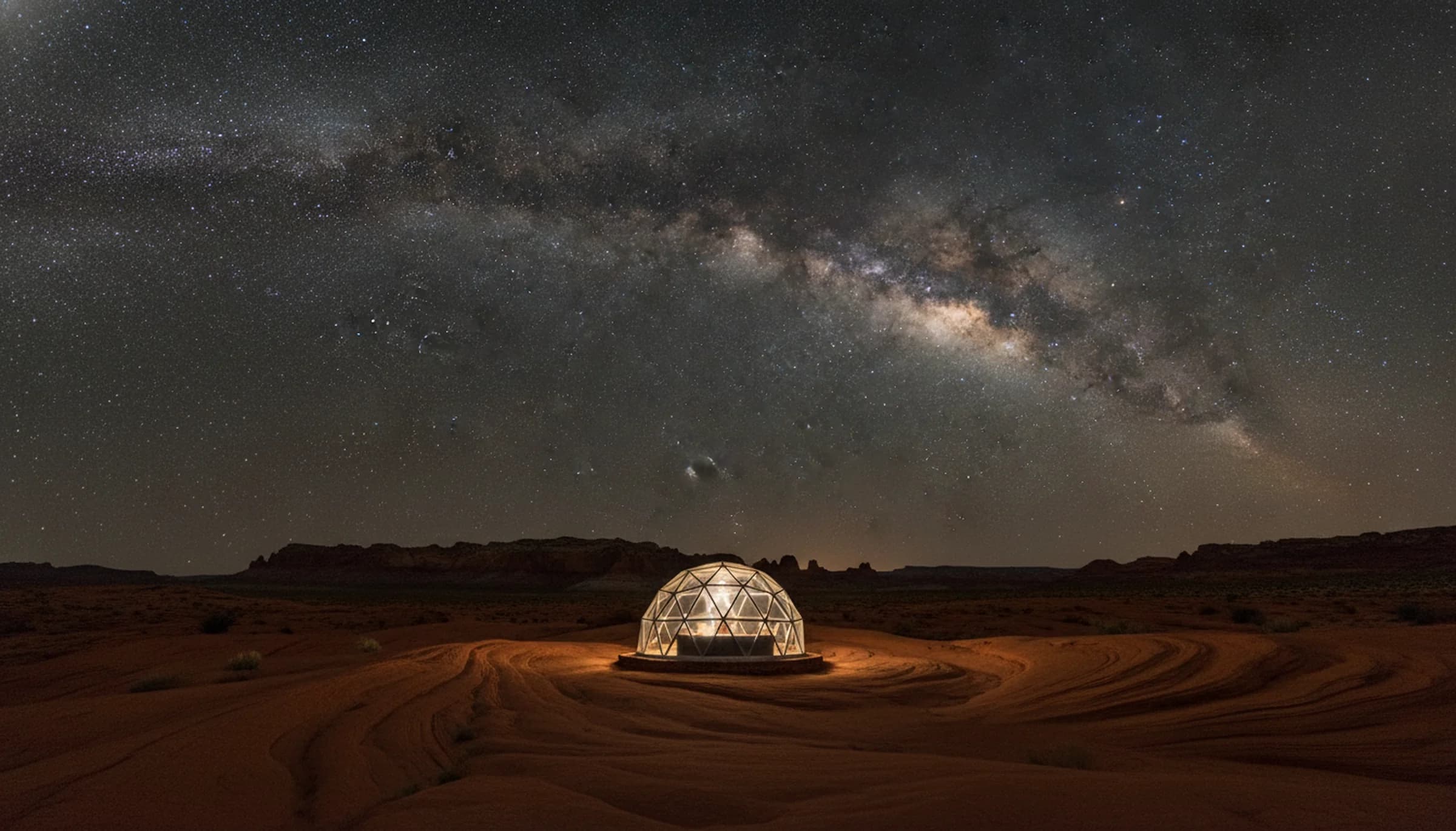 The Milky Way arching over a lit geodesic dome on red slickrock in a certified International Dark Sky Park