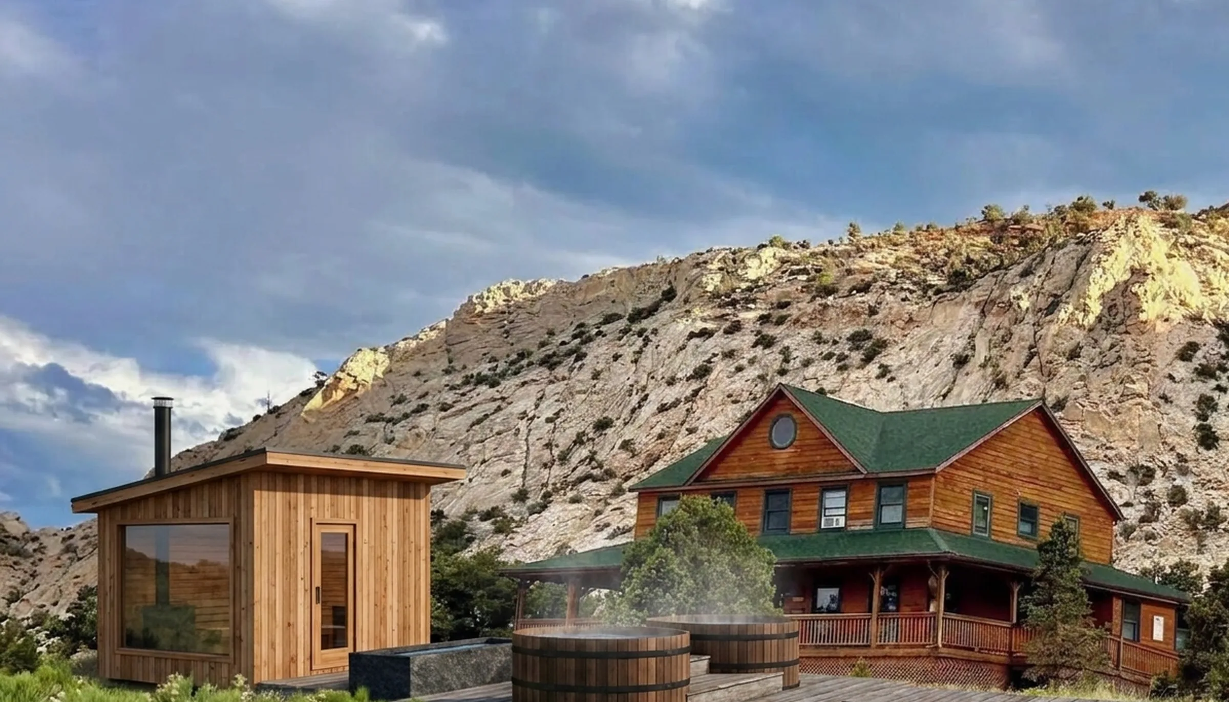 Visualisation of a planned cedar sauna, cold plunge and two soaking tubs on a timber deck beside a timber lodge, under a white sandstone ridge in Capitol Reef Country