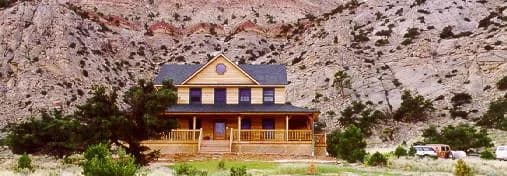 The Muley Twist Inn in its first years, a new timber building with a wraparound porch below the cliff, from the inn's 2003 website