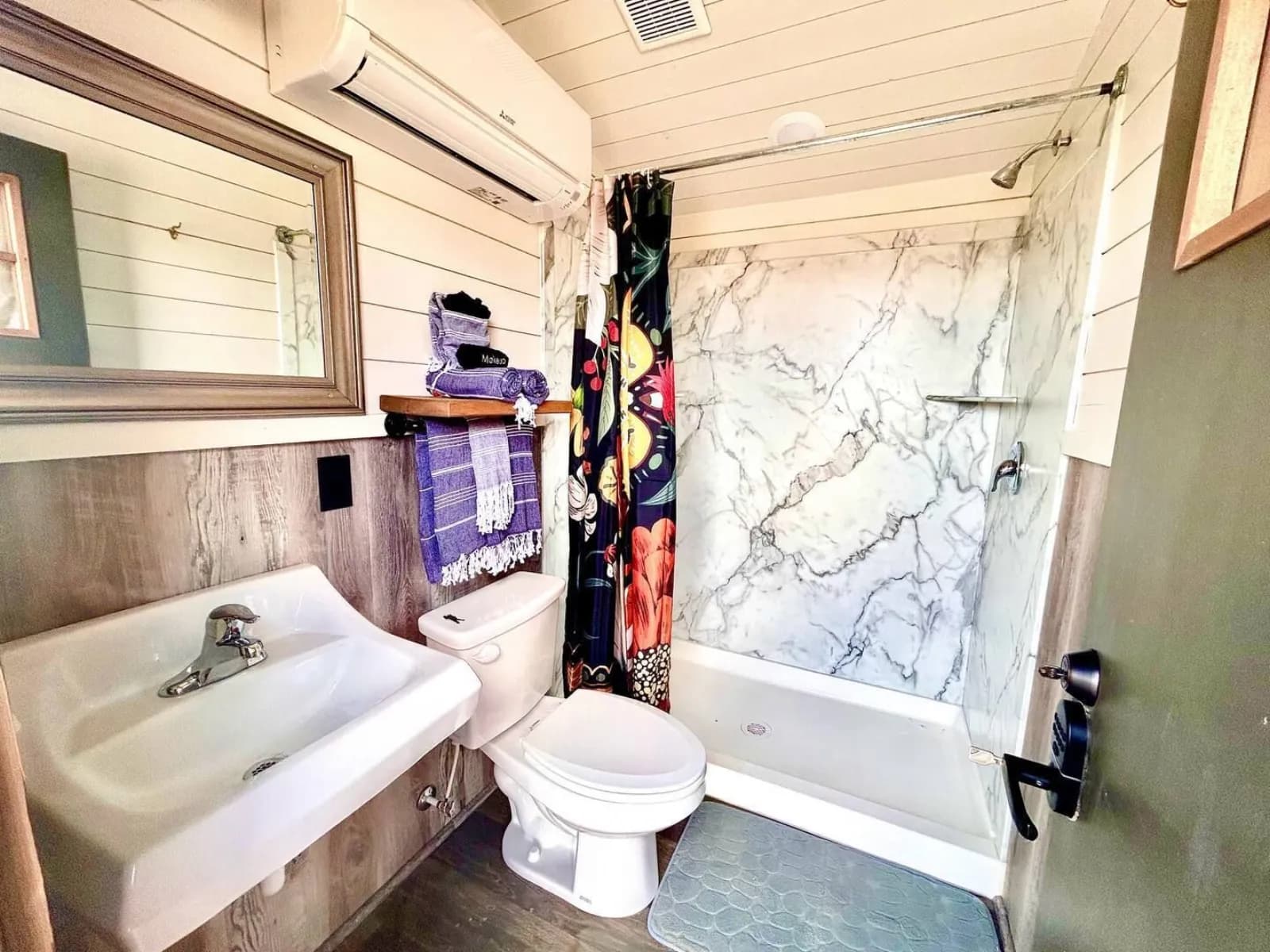 A private bathroom in The Lodge, with a basin, mirror and a bath with an overhead shower