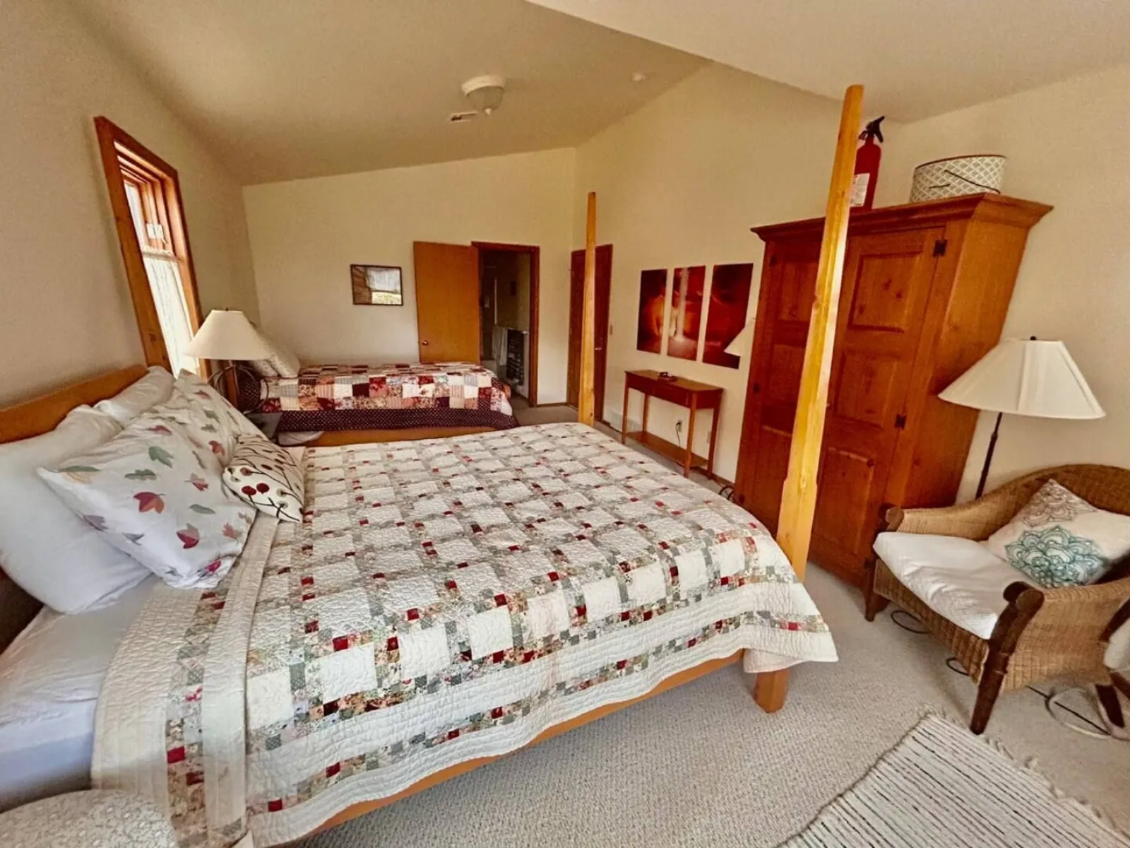 A bedroom in The Lodge with a quilted double bed, bedside lamp and a wooden wardrobe