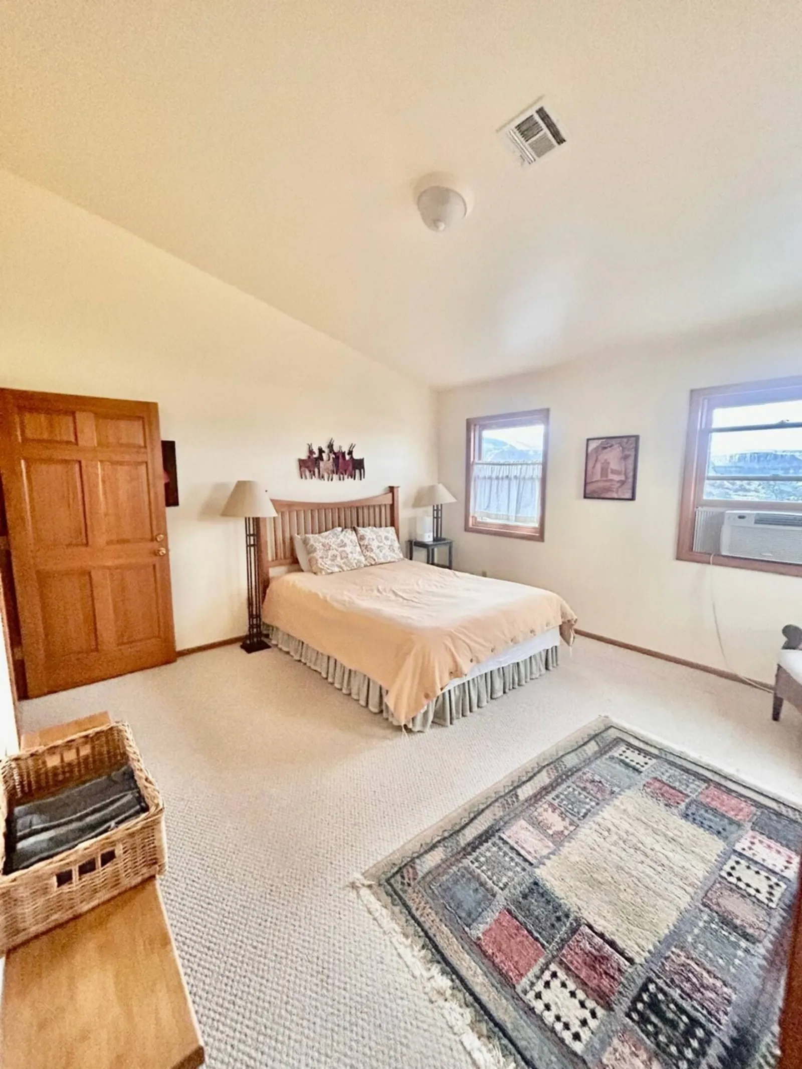 A bedroom in The Lodge with a patterned rug, bed and a window onto the valley