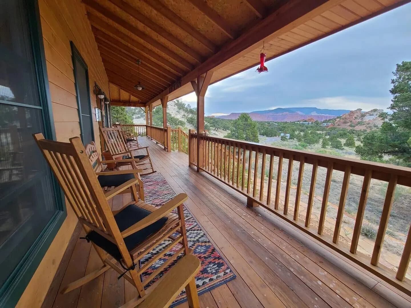 The Lodge's covered wraparound deck, with timber rocking chairs looking out over the valley to the mesas beyond