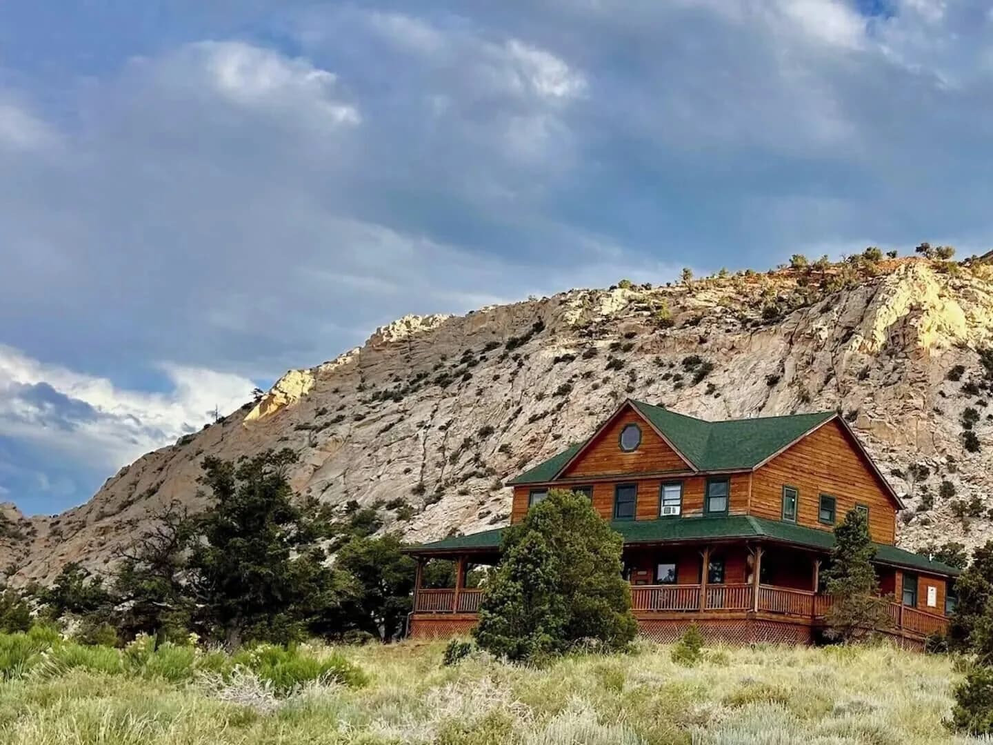 The Lodge seen from the desert below — a two-storey timber building with a wraparound covered deck, set against a sandstone ridge