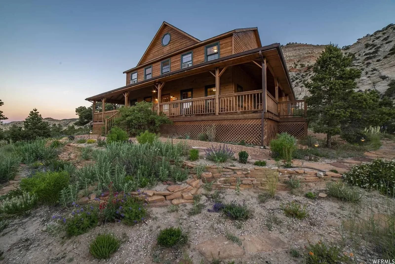 The Lodge seen from the desert below — a two-storey timber building with a wraparound covered deck, set against a sandstone ridge